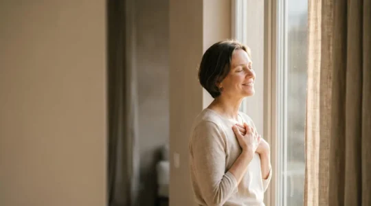 Personne au visage apaisé et souriant, baignée dans une lumière matinale douce, symbolisant la joie intérieure durable