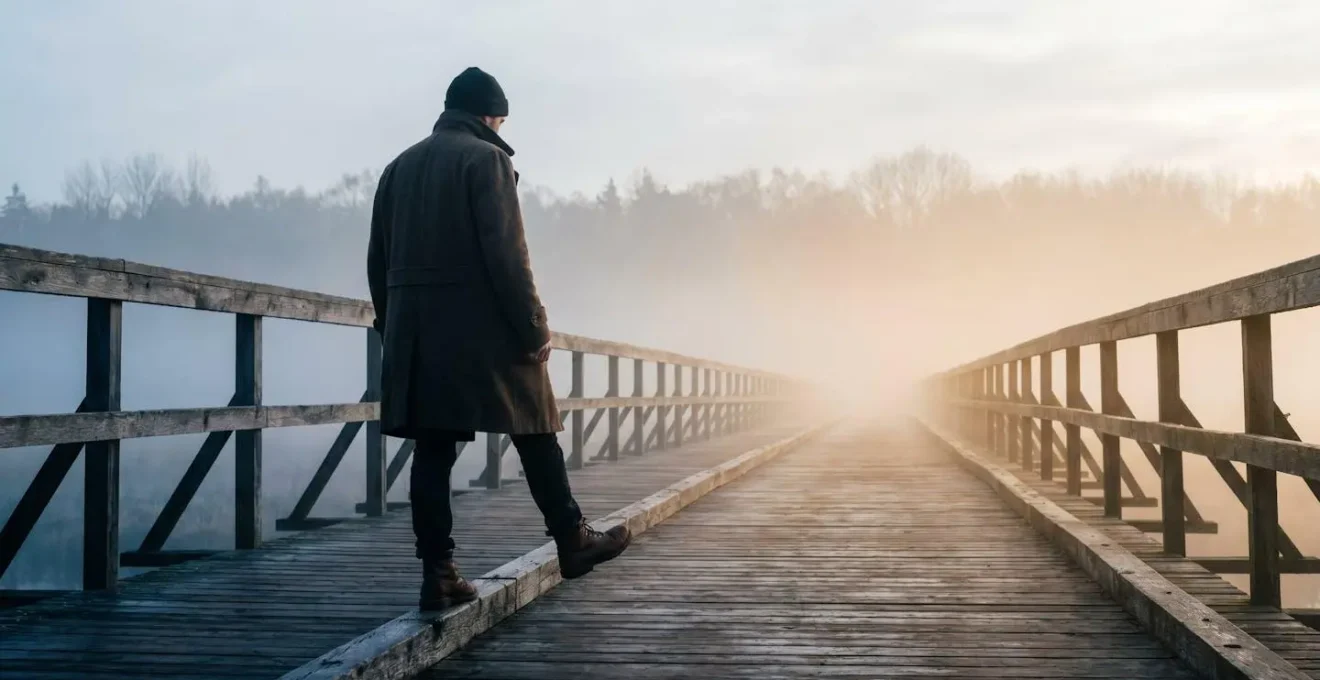 Silhouette d'une personne face à un pont suspendu dans la brume, symbolisant l'écart entre les bonnes intentions et le passage à l'action